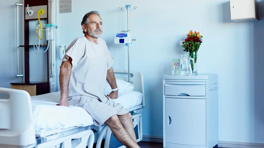 man sitting on the edge of a hospital bed