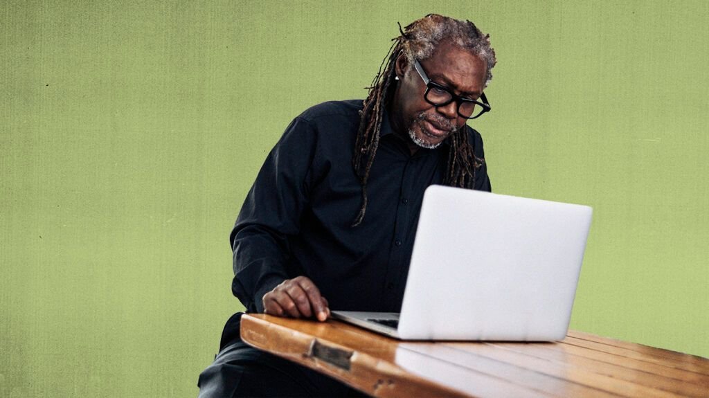 photo of middle-aged black man wearing glasses on laptop researching Medicare Plan G Pros and Cons, isolated over green background