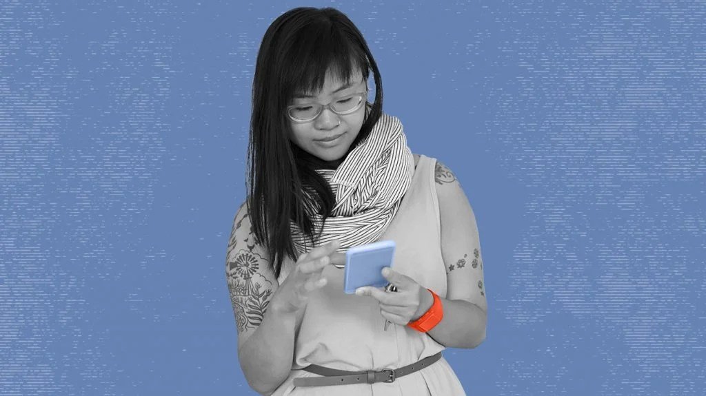 Black and white photo of woman using smartphone to look at Nurx website, isolated over blue background