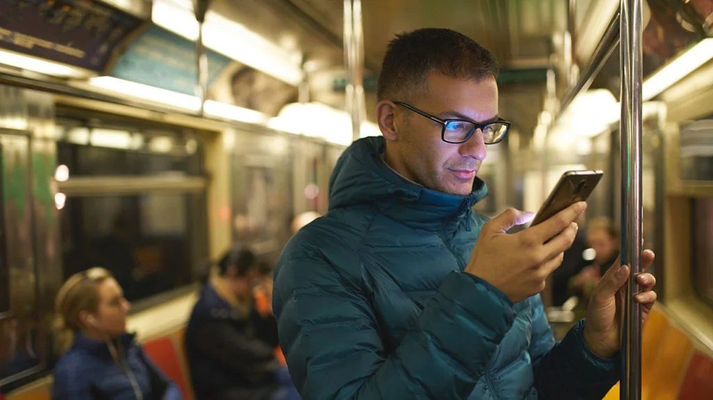 a man looking at his phone on the subway and experiencing the Negative effects of technology
